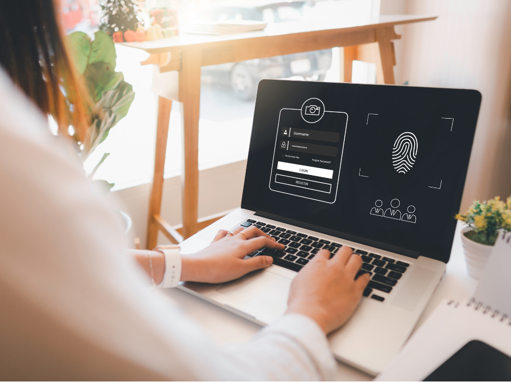 Person using a laptop with a login screen displaying username, password, and fingerprint security options. The screen highlights biometric authentication, emphasizing cybersecurity measures
