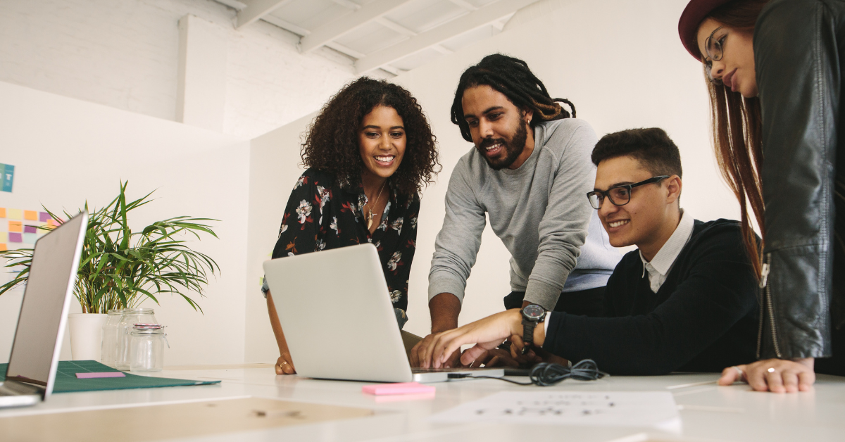 Coworkers gathered around a computer smiling and happy that their software is working smoothly