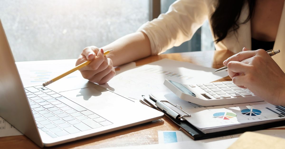 Two women are using laptops and computers to figure out their behavioral health revenue management.
