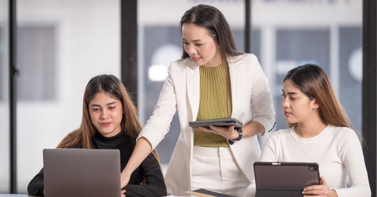 Three women in an office using devices to review trends in mental health.