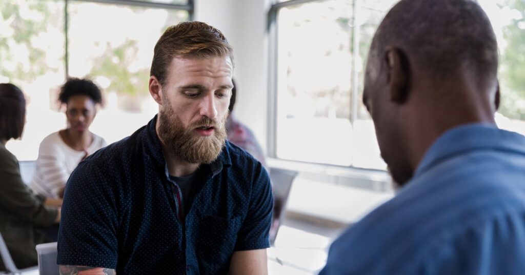 A man in a mobile crisis team talks to another man in a room.