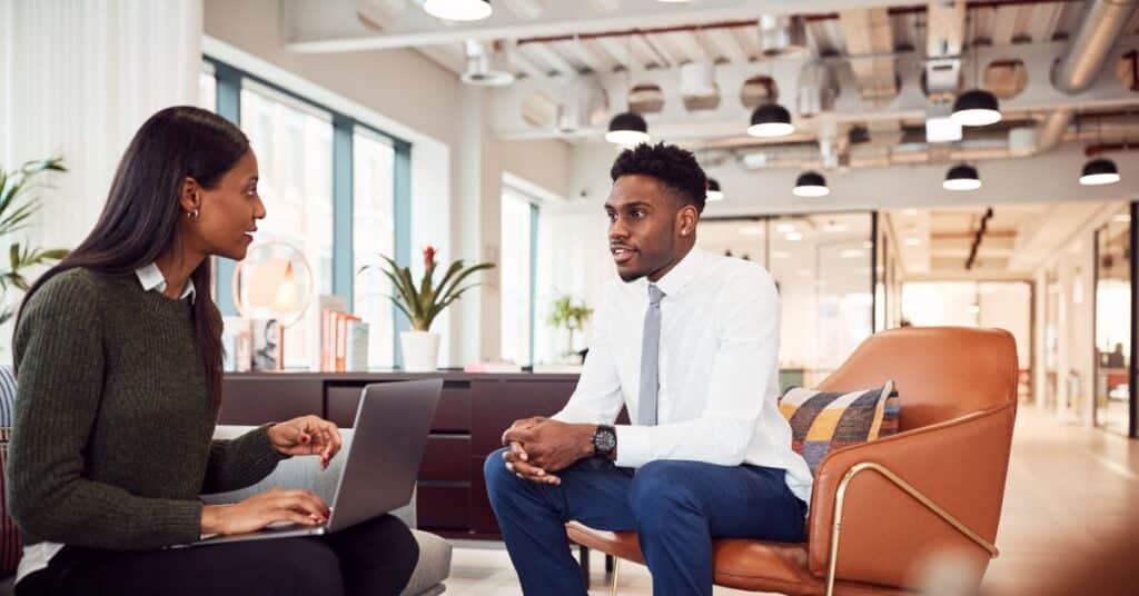 Two business professionals having a discussion in a modern office, addressing workforce shortage challenges.