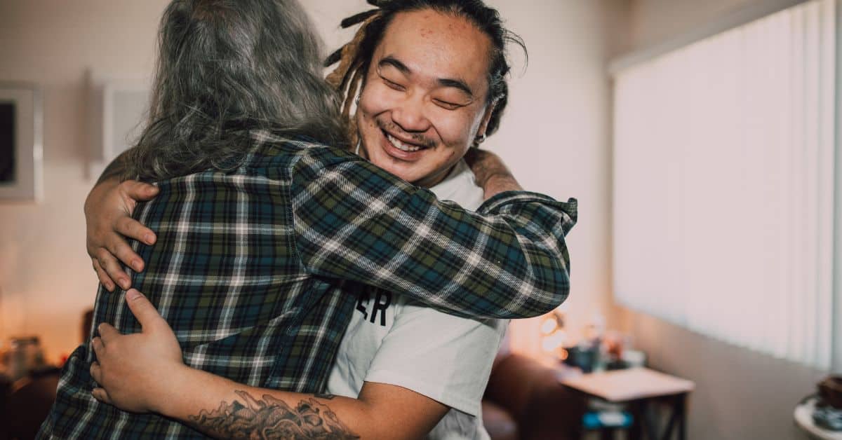 Two people warmly embrace in a supportive indoor setting, representing recovery support and the impact of Medicaid work requirements behavioral health services.